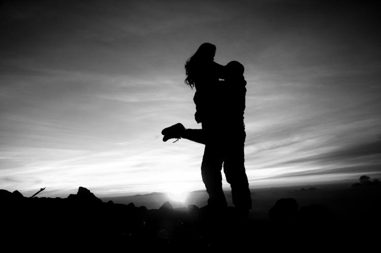 A Silhouette Of A Man Carrying And Hugging A Woman 