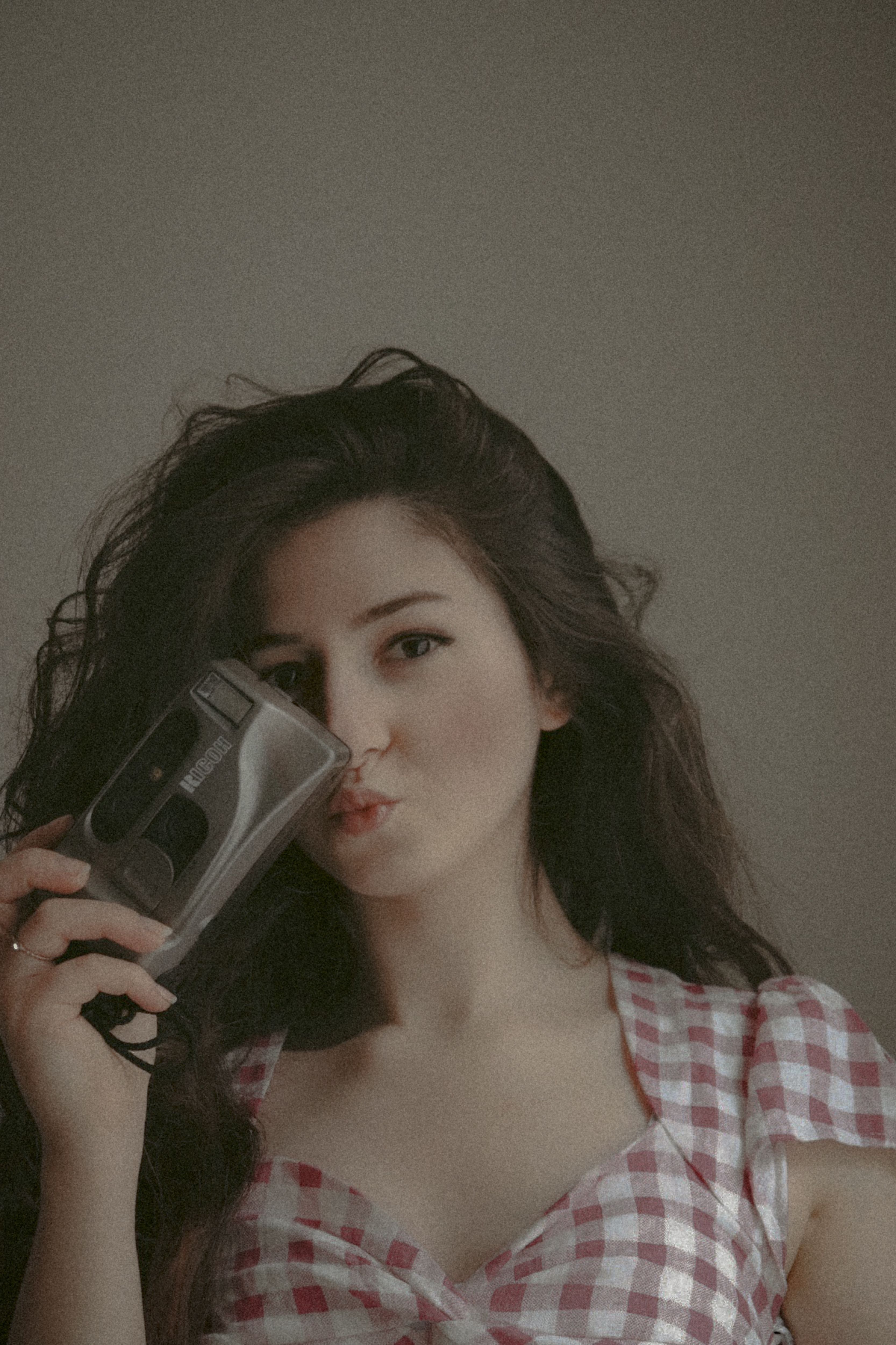 Fashionable woman in plaid poses with a vintage camera, creating a nostalgic mood.