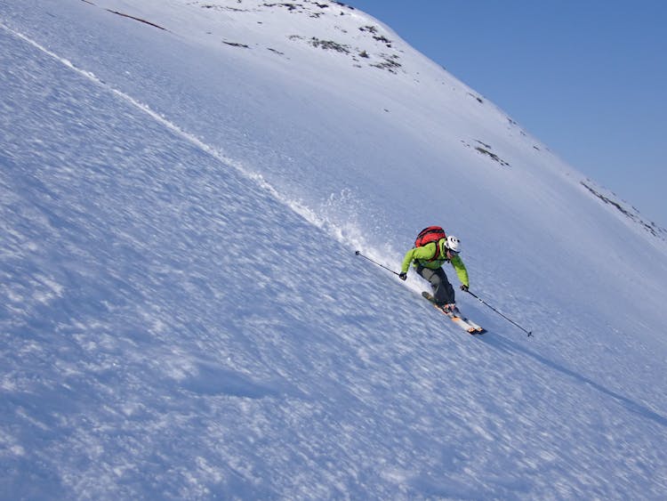 Man In Green Jacket And Red Back Pack Skiing