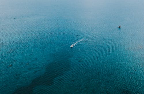 A White Motorboat Speeding on Blue Sea Causing Waves