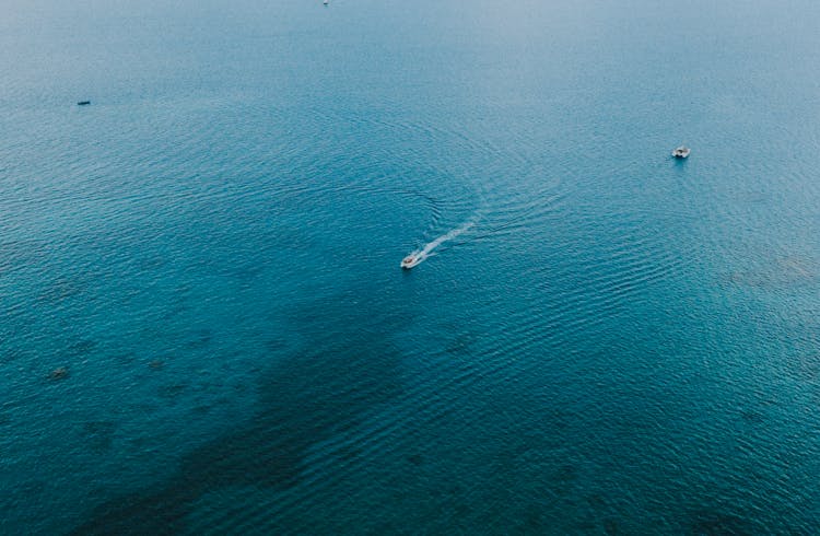 A White Motorboat Speeding On Blue Sea Causing Waves