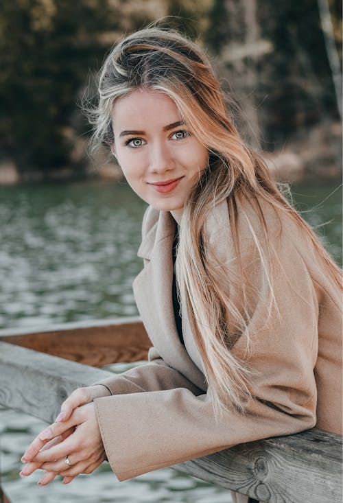 Woman in Brown Coat Leaning on a Wooden Railing