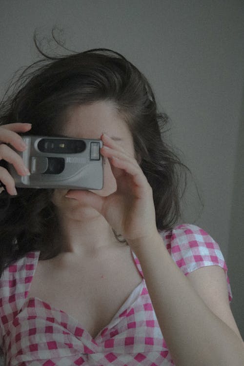 Woman in Pink and White Plaid Top Holding a Silver and Black Camera