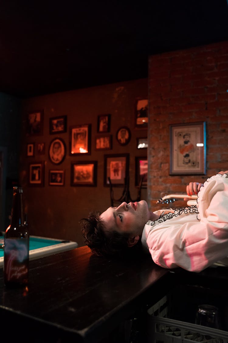 Man In White Long Sleeve Shirt Lying On Bar Counter