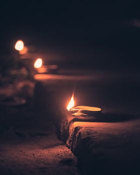Peaceful evening scene with traditional Indian diya lamps glowing in the dark, symbolizing celebration and spirituality.