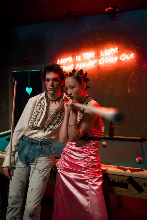 Free Two people in punk fashion pose at a pool table with neon lights. Stock Photo