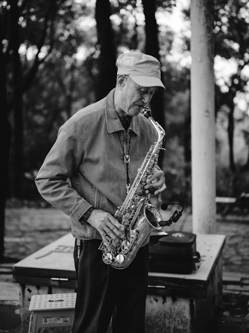 An Elderly Man Playing on Saxophone in Park 