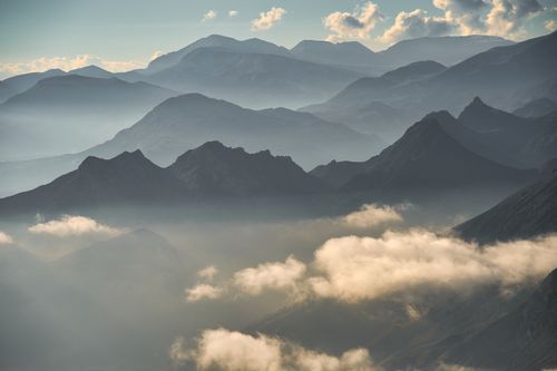 Free Breathtaking view of cloud-covered mountains at sunrise with misty peaks. Stock Photo