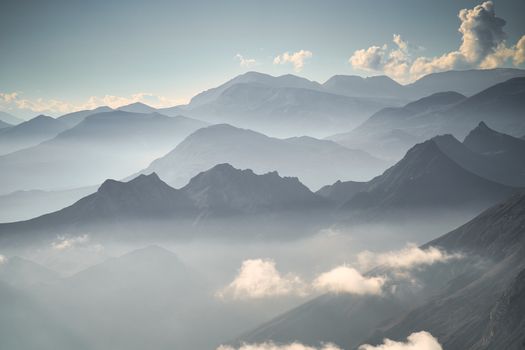 Breathtaking view of a mist-covered mountain range under a clear blue sky at dawn.