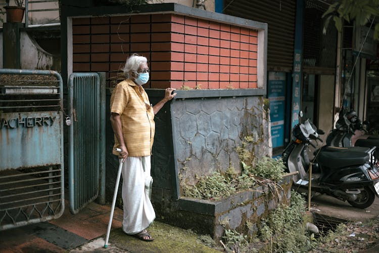 An Elderly Woman Wearing Face Mask While Holding A Cane