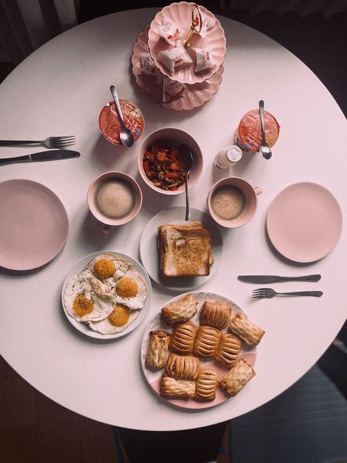 Free A stylish breakfast arrangement with pastries, eggs, and coffee on pink dishware. Stock Photo
