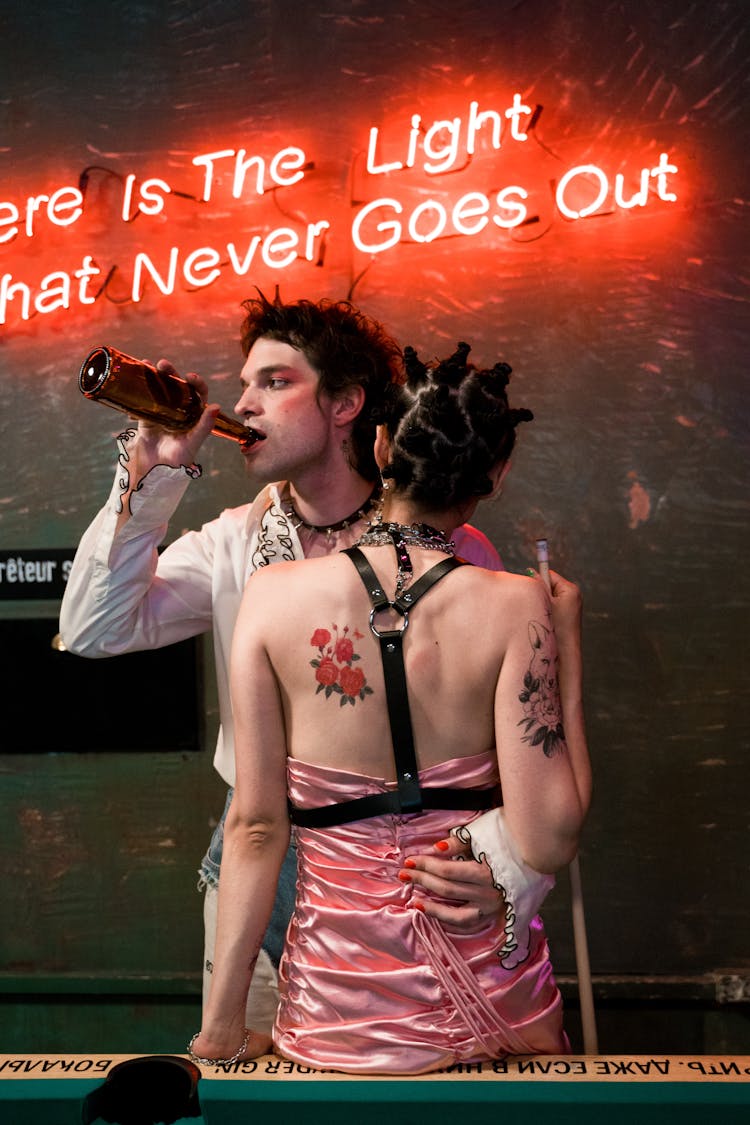 A Man Drinking Beer While Embracing His Partner