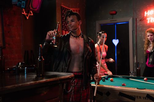 Free Group of diverse friends enjoying billiards in a punk-themed bar setting. Stock Photo