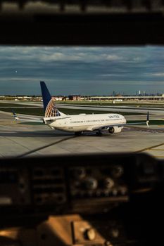 View of a commercial airplane on the airport tarmac from inside a cockpit during daytime.