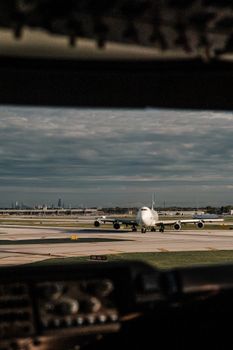 A commercial airplane taxis on a runway at a busy airport during the day.