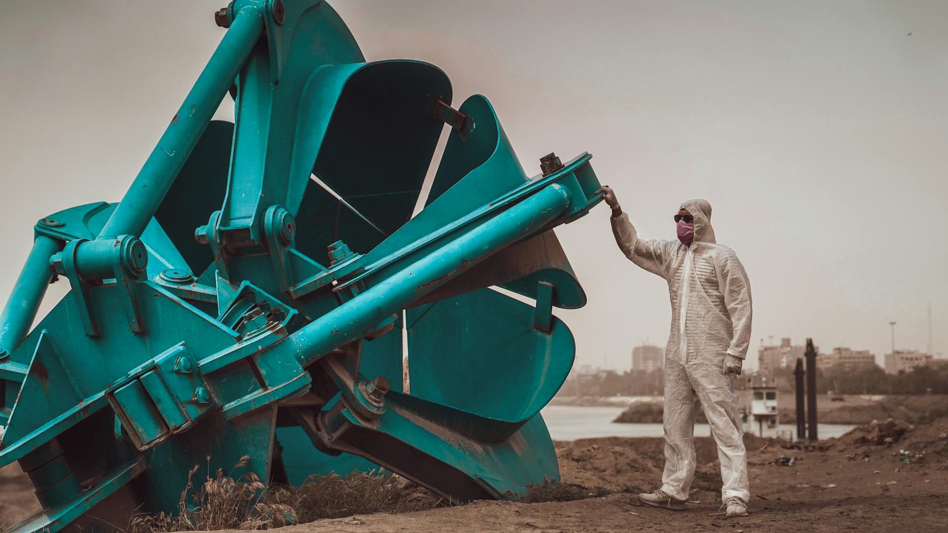 A Man in a Cleanroom Suit Standing next to Heavy Machinery