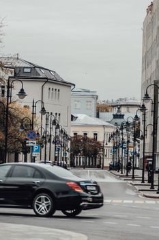 Urban street scene featuring cars, classic buildings, and street lamps on a cloudy day.