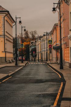 Serene empty street with historic buildings and autumn foliage, creating tranquil urban ambiance.