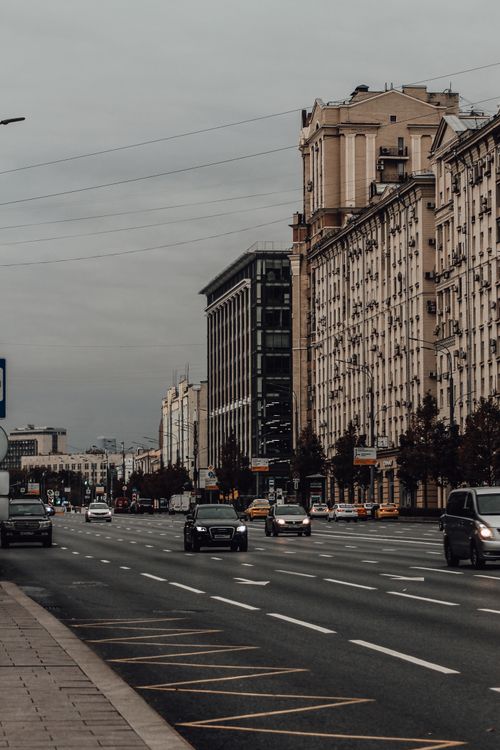 Free Wide city street view featuring classic architecture and vehicles on a cloudy day. Stock Photo