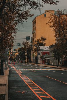 Deserted city street scene in autumn with colorful leaves and urban architecture.