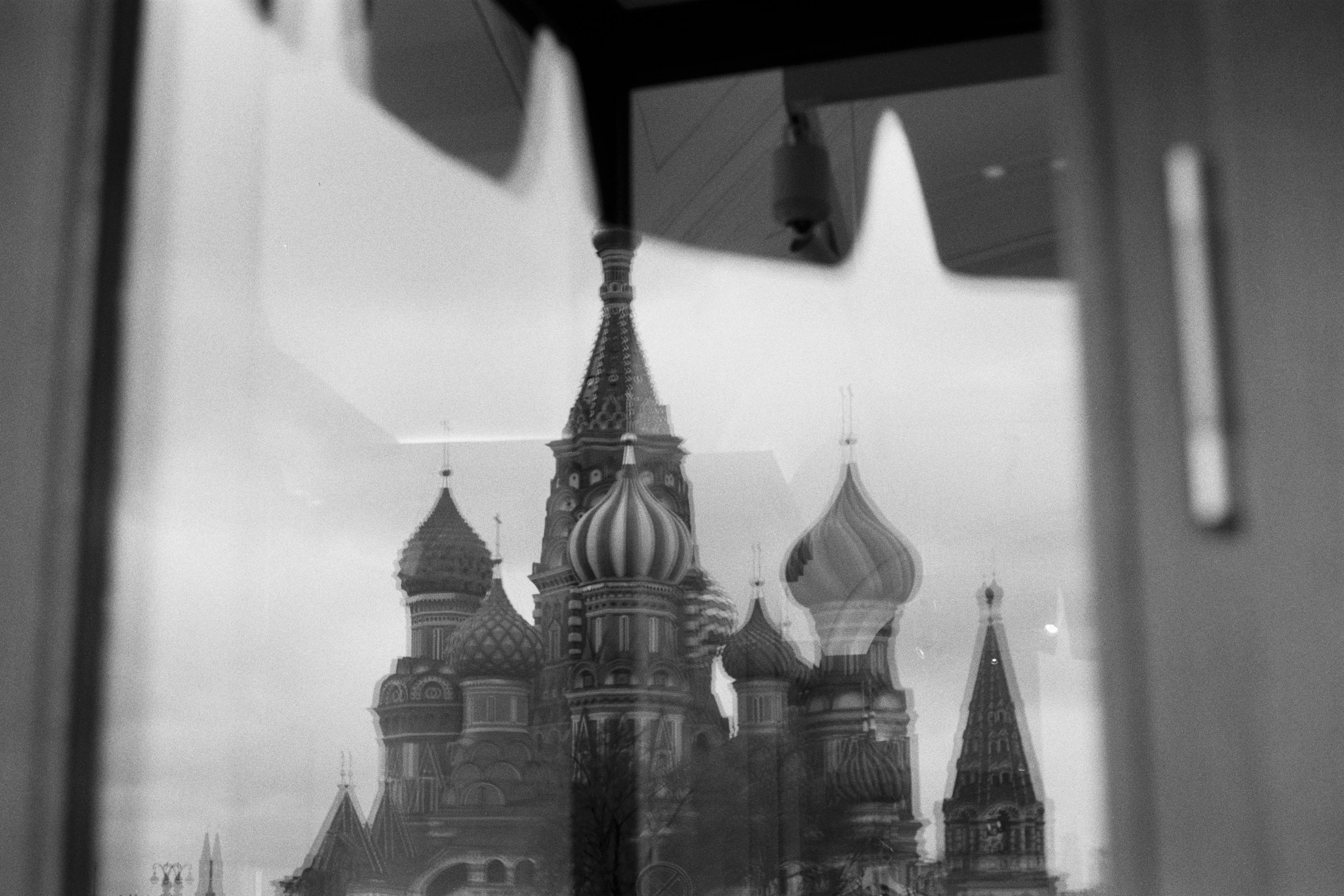 A striking reflection of Saint Basil's Cathedral captured in monochrome through a glass window.