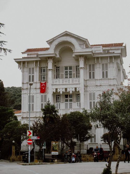 Free Beautiful classic mansion adorned with a Turkish flag, surrounded by lush greenery and street view. Stock Photo