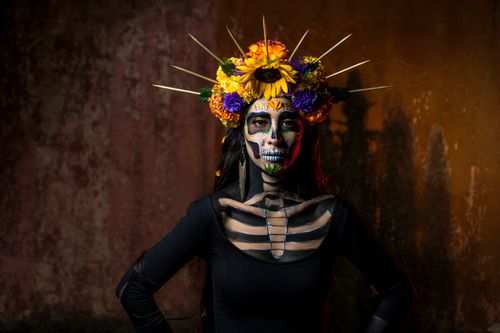 Free Vibrant portrait of a woman in traditional Day of the Dead face paint with floral headdress. Stock Photo