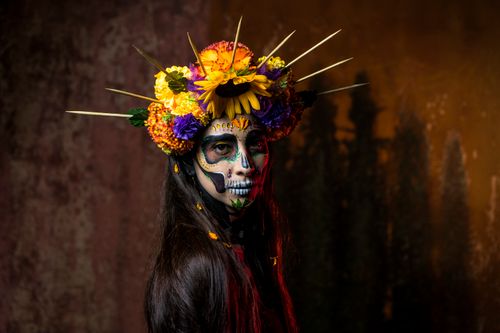 Free Striking portrait of a woman with Day of the Dead makeup and floral crown in a moody setting. Stock Photo