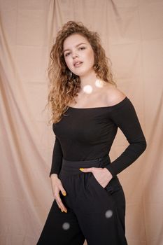 Stylish woman in black off-shoulder top and pants, posing indoors.