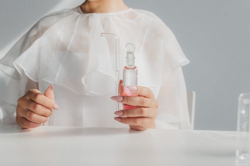 Free Close-up of a scientist holding a flask with pink liquid in a laboratory setting. Stock Photo
