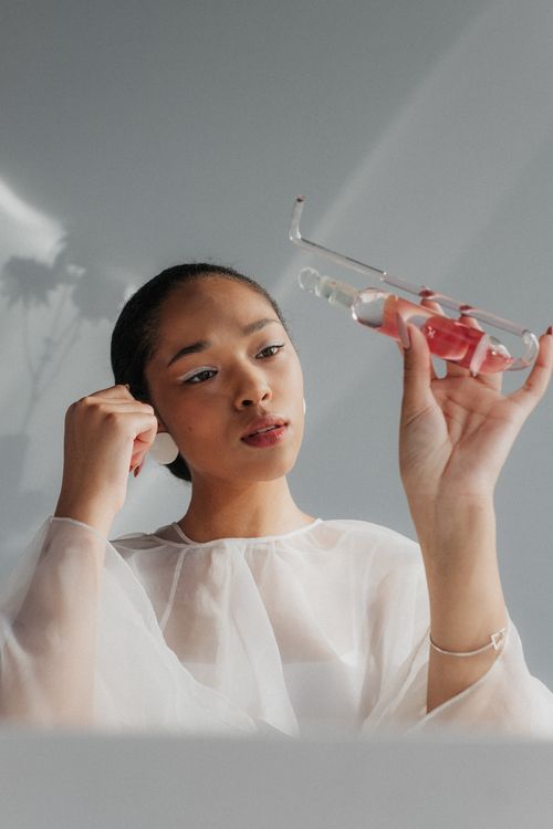 Free Focused woman in lab coat examining a test tube in a light-filled laboratory setting. Stock Photo