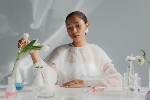 A stylish woman in a lab setting with tulips and glassware, blending science and elegance.