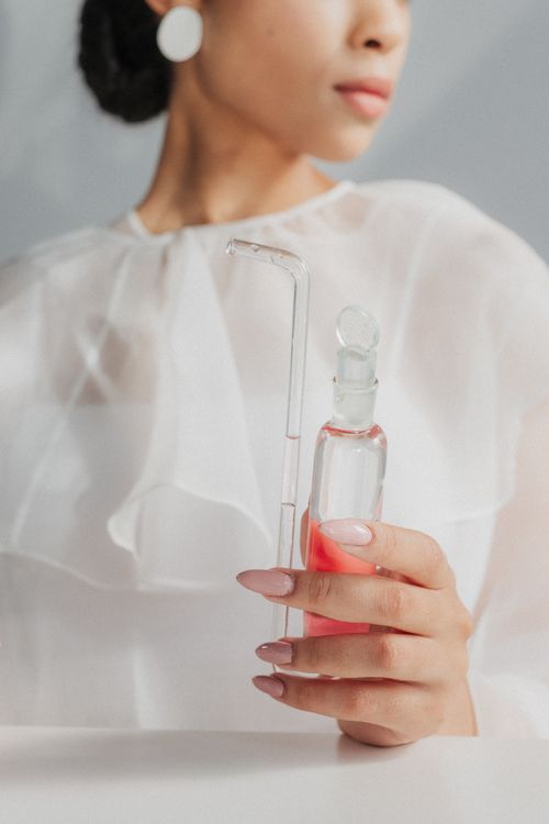 Free Close-up of a woman holding a glass flask with pink liquid, highlighting elegance and style. Stock Photo