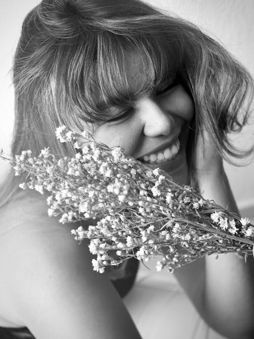 Free A Female Smiling and Holding Flowers in Black and White  Stock Photo