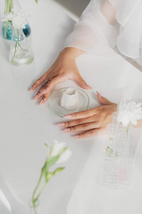 Unrecognizable Female Hands Embracing Petri Dish on White Table Top