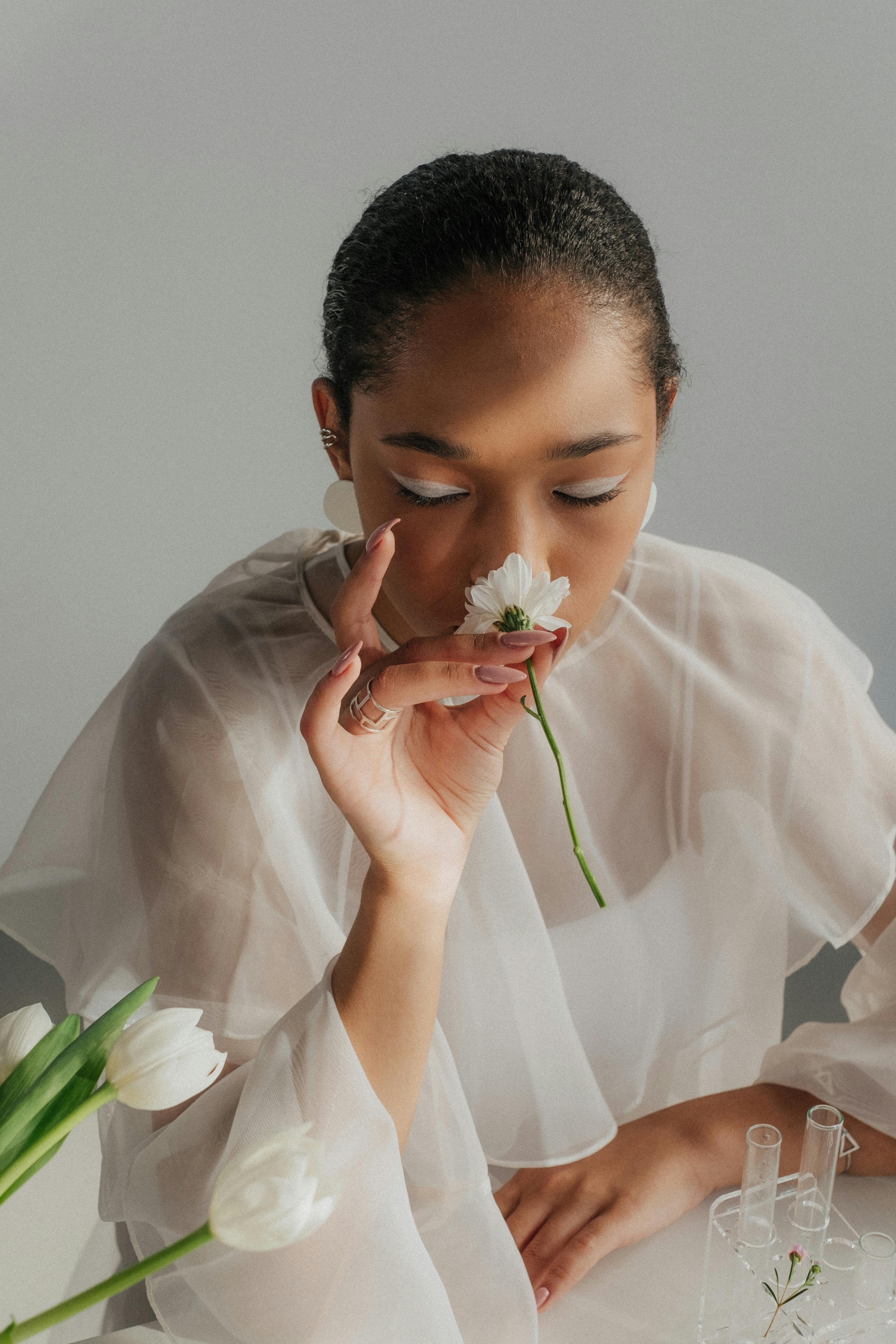 woman holding and smelling white flower