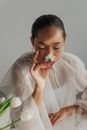 Woman Holding and Smelling White Flower