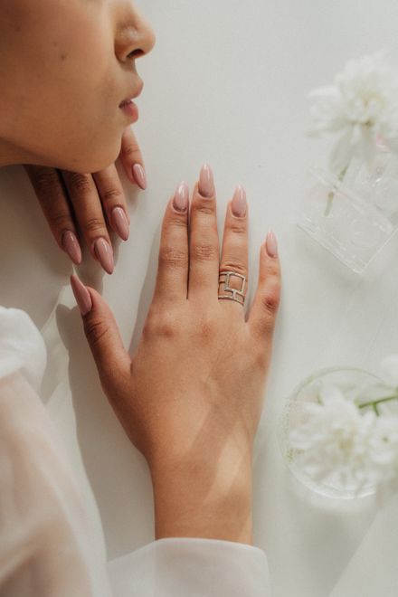 Nude almond nails resting beside white blooms — photo by Ron Lach on Pexels