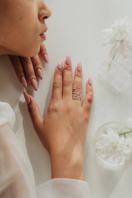Mãos com unhas em tom nude feitas em salão