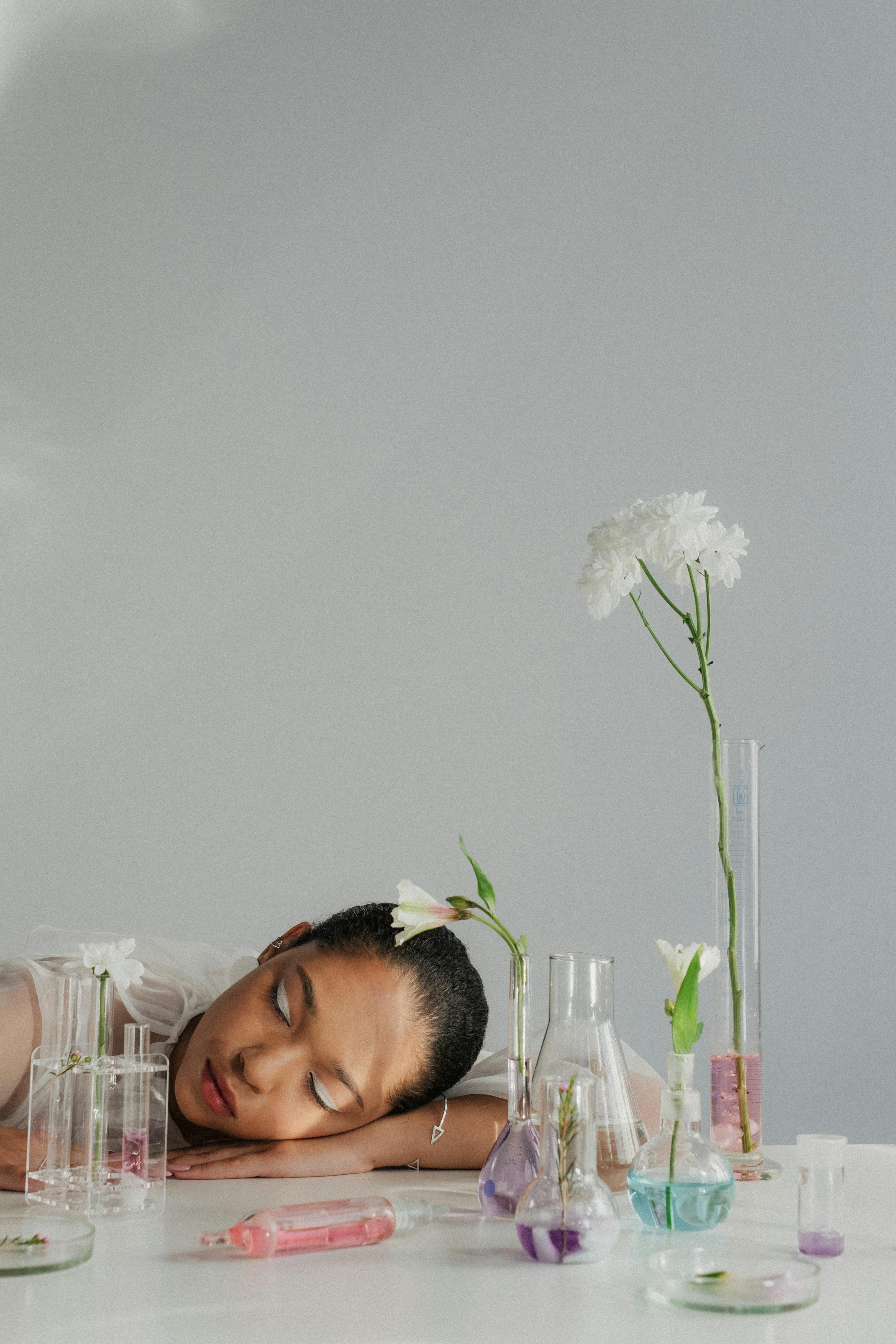 Woman resting among laboratory flasks, used here to illustrate sleep disruption and the symptom overlap of perimenopause.