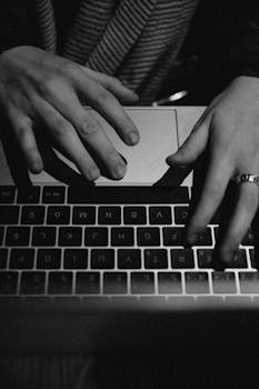 Monochrome image showcasing hands typing on a laptop, focusing on technology and communication.