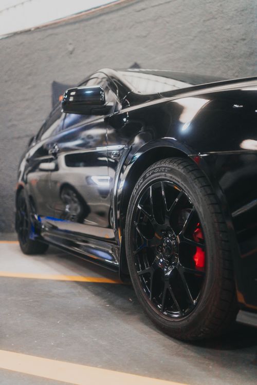 Free Close-up of a glossy Mitsubishi Lancer Evolution parked indoors showcasing its sleek design and shining wheels. Stock Photo