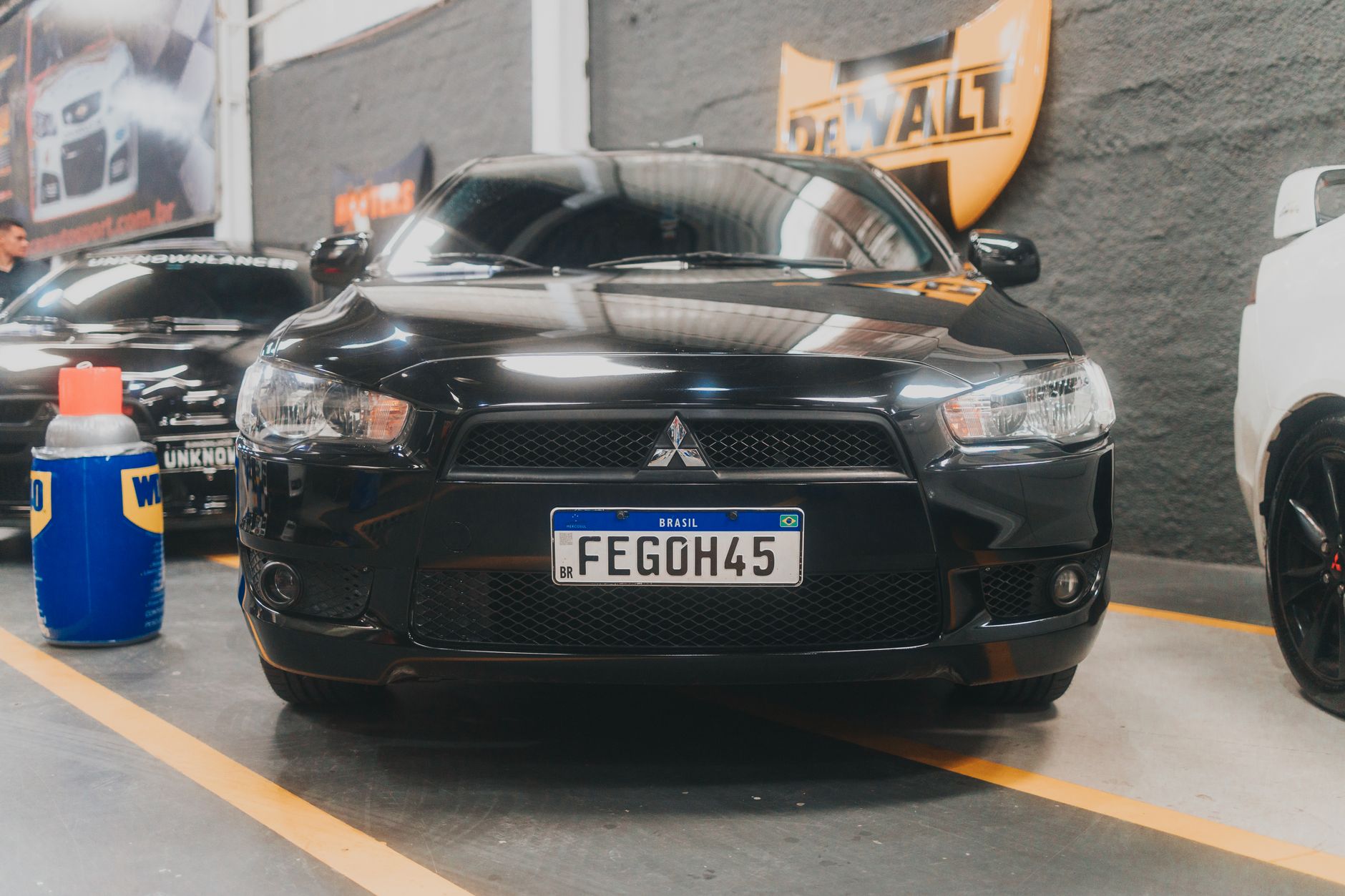 Front view of a black Mitsubishi Lancer parked in an indoor garage with visible branding and license plate.