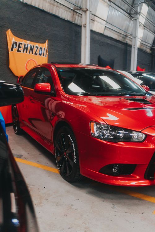 Free Vibrant red Mitsubishi Lancer Evolution showcased indoors, highlighting its sleek design and shiny surface. Stock Photo