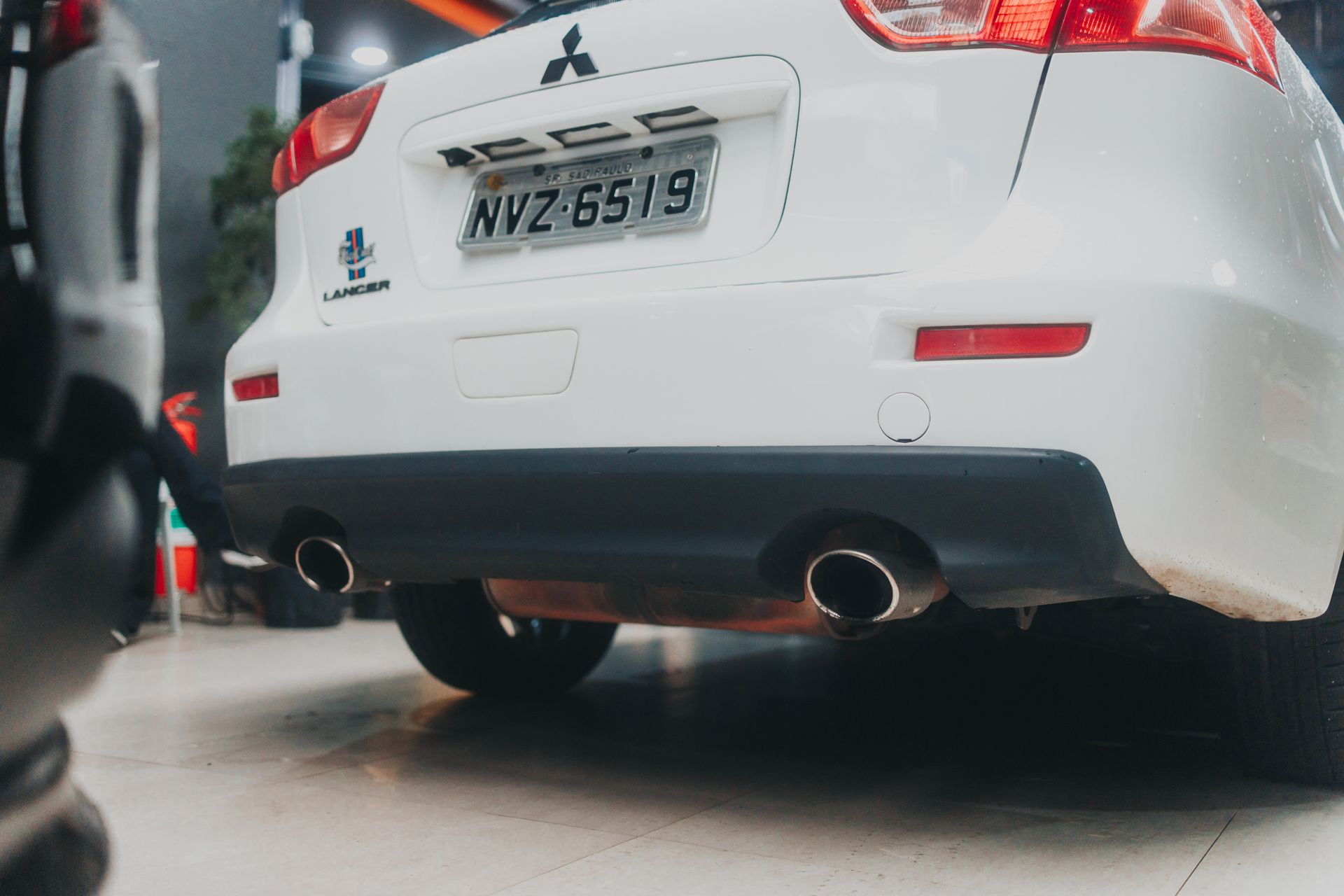 Close-up of a white Mitsubishi Lancer showcasing its exhaust and rear design in an indoor setting.