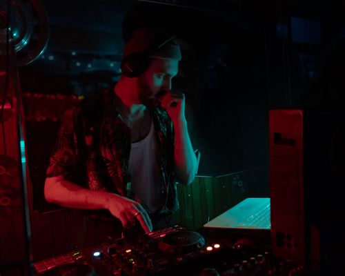 Free DJ mixing tracks in a dimly lit club with vibrant lighting. Stock Photo