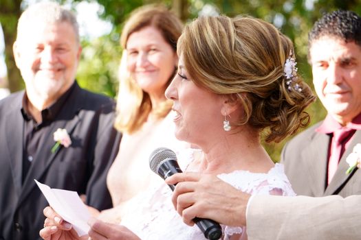 A woman delivering a heartfelt speech at an outdoor wedding ceremony.