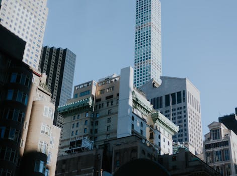 Low angle shot of diverse skyscrapers against a clear blue sky creates a striking city skyline.