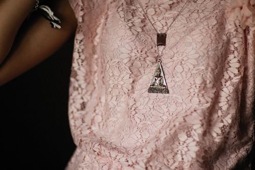 Free Stylish close-up of a Buddha pendant on a lace pink top, perfect for fashion and spirituality themes. Stock Photo