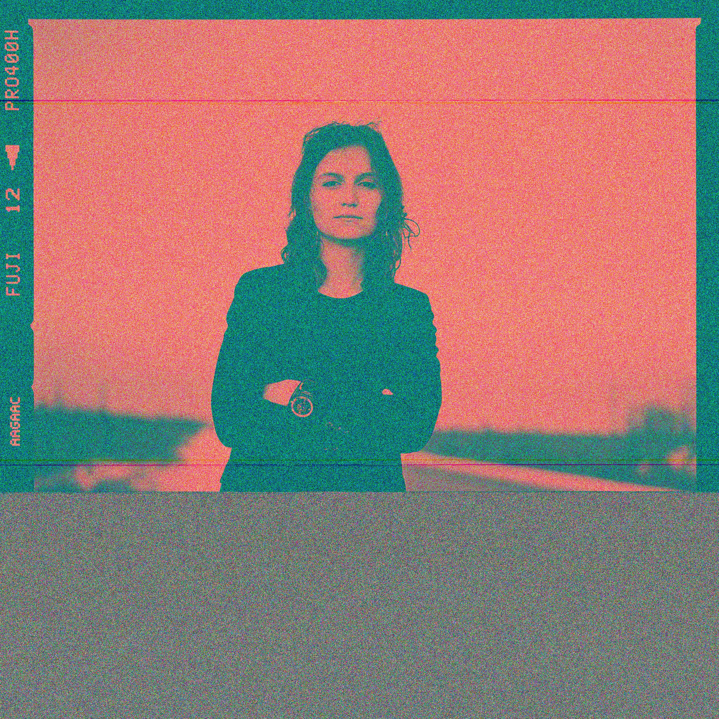 A retro film-style portrait of a woman posing confidently outside.